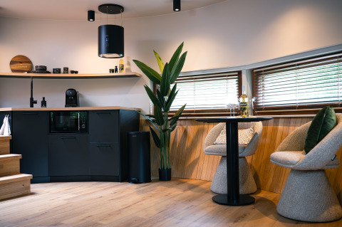 Modern interieur in The Nutshell tiny house met keuken, zithoek en grote ramen in Nederland.
