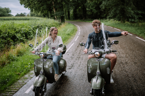 Twee mensen op scooters maken plezier dicht bij The Nutshell, Den Blanken, op het platteland van Nederland.