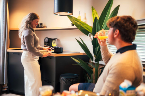 Couple enjoys time in The Nutshell tiny house with modern kitchen at Recreation Park Den Blanken, Netherlands.