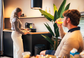 Couple enjoys time in The Nutshell tiny house with modern kitchen at Recreation Park Den Blanken, Netherlands.