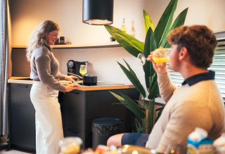 Koppel geniet in The Nutshell tiny house met moderne keuken op Recreatiepark Den Blanken, Nederland.