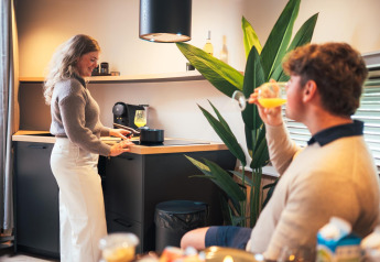 Coppia si gode la tiny house The Nutshell con cucina moderna al Recreation Park Den Blanken, Paesi Bassi.