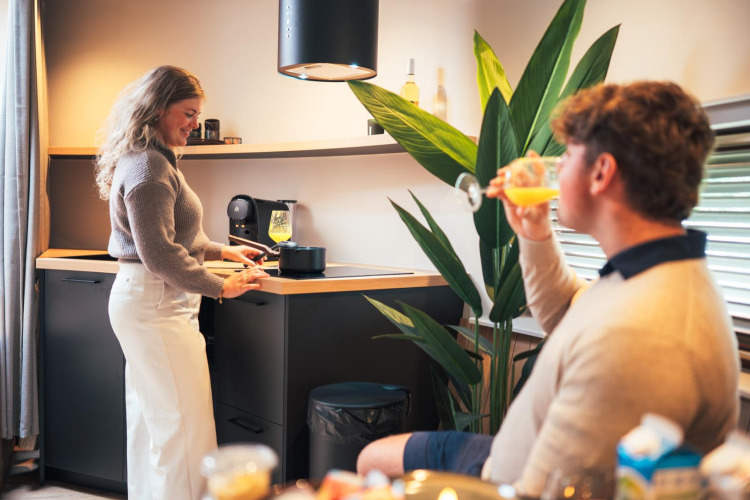 Pareja disfruta en la tiny house The Nutshell con cocina moderna en Recreation Park Den Blanken, Países Bajos.