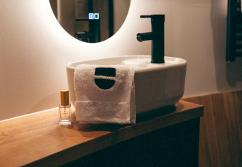 Modernes Bad mit Waschbecken, Handtuch und Duftflasche in The Nutshell, Den Blanken, Niederlande.