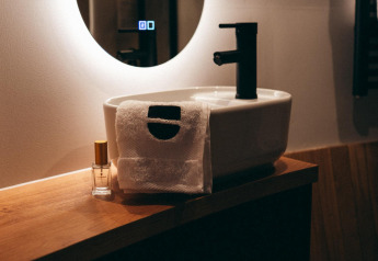 Modernes Bad mit Waschbecken, Handtuch und Duftflasche in The Nutshell, Den Blanken, Niederlande.