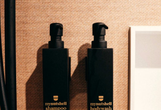 Two black bottles labeled 'mynutshell shampoo' and 'mynutshell bodywash' mounted on a bathroom wall.