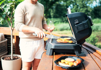 Ein Mann grillt Essen auf einer Terrasse eines Tiny Houses mit Whirlpool und Sauna im Recreation Park Den Blanken.