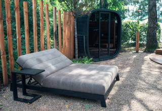 Modern outdoor relaxation area with lounge chair, sauna hut, and wood fence at Den Blanken, Netherlands