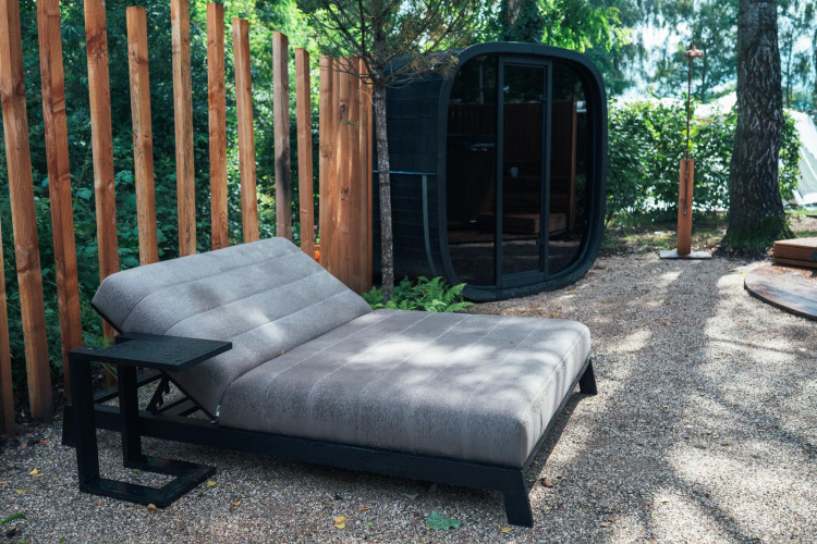 Zona de relax exterior con tumbona moderna, sauna y cerca de madera en Den Blanken, Países Bajos