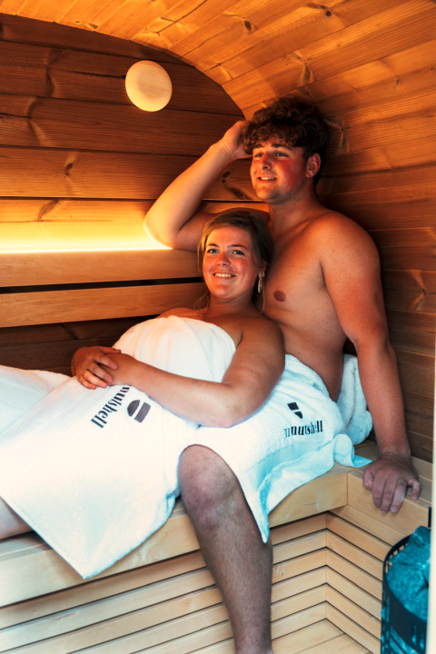 Two people relax in the sauna at The Nutshell tiny house with hot tub at Den Blanken, Netherlands.