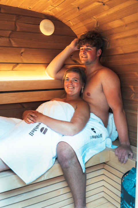 Twee mensen ontspannen in de sauna van The Nutshell tiny house met hot tub in Den Blanken, Nederland.