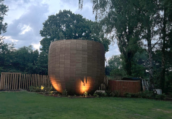 Winziges Holzhaus The Nutshell mit Hot Tub und Sauna, beleuchtet im Freizeitpark Den Blanken, Niederlande.
