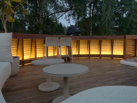 Evening deck at The Nutshell in Den Blanken Park, Netherlands, warmly lit with cozy outdoor furniture.