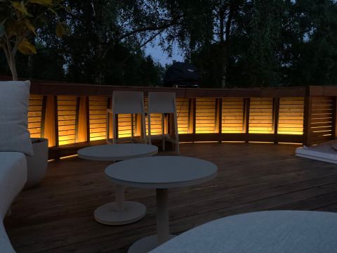 Udendørs terrasse ved Døden Blanken, Nederlandene, oplyst i skumringen med moderne møbler.