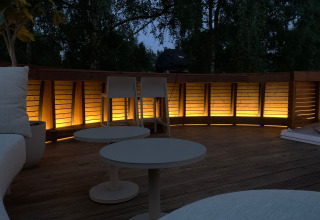 Udendørs terrasse ved Døden Blanken, Nederlandene, oplyst i skumringen med moderne møbler.