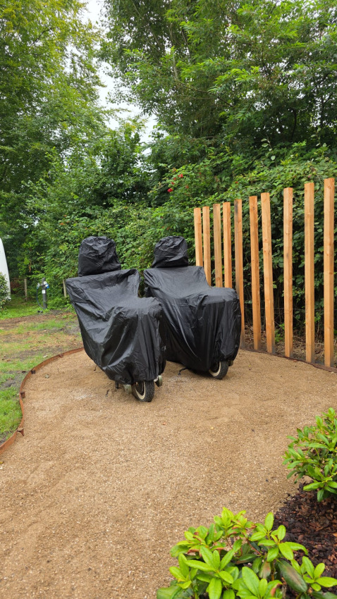 Twee bedekte ligstoelen bij houten omheining in tuin van The Nutshell aan Den Blanken, Nederland.