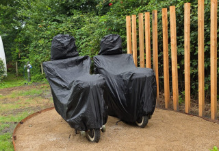 To overdækkede liggestole ved siden af et træhegn i en grøn have ved The Nutshell i Den Blanken, Holland.