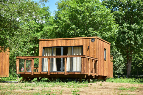 Houten lodge in Cocoon de la Semois, Hameau de la Semois, België, omringd door weelderige bomen.