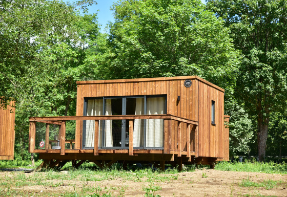 Holzlodge im Cocoon de la Semois, Hameau de la Semois, Belgien, eingebettet in grüne Bäume und Natur.