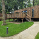 Modern wooden lodges on stilts with deck terraces, nestled in a lush green forest with winding paths.