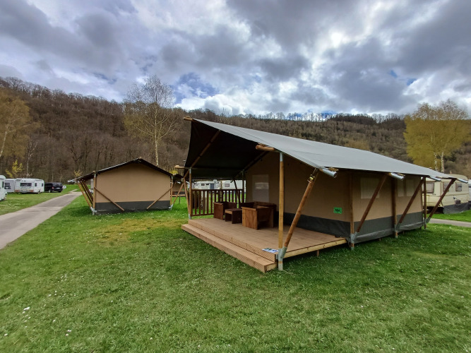 Safarizelt auf Camping la Roche in Belgien, umgeben von grünen Hügeln und Wohnwagen.