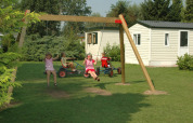 Children playing on swings and pedal karts in front of mobile homes at a holiday park in Gelderland, Netherlands.