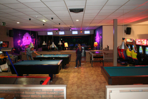 Sala de ocio en Recreatiepark de Scherpenhof con mesas de billar, máquinas recreativas y bolera en Gelderland.
