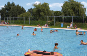 Børn og voksne nyder en solrig dag i udendørs poolen i Recreatiepark de Scherpenhof, Gelderland.