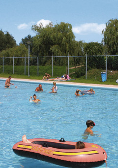 Børn og voksne nyder en solrig dag i udendørs poolen i Recreatiepark de Scherpenhof, Gelderland.
