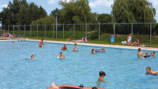 Børn og voksne nyder en solrig dag i udendørs poolen i Recreatiepark de Scherpenhof, Gelderland.