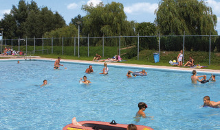 Gezinnen ontspannen en zwemmen in het openluchtzwembad van Recreatiepark de Scherpenhof, Gelderland.