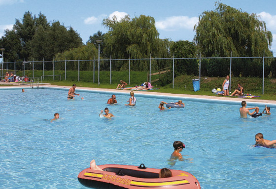 Børn og voksne nyder en solrig dag i udendørs poolen i Recreatiepark de Scherpenhof, Gelderland.
