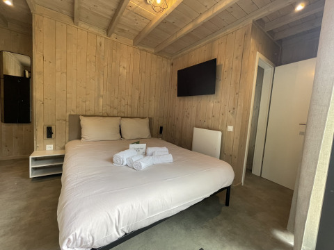 Moderne kamer in lodge Cocoon de la Semois, Hameau de la Semois, België, met houten muren en een tweepersoonsbed.