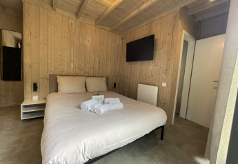 Moderne kamer in lodge Cocoon de la Semois, Hameau de la Semois, België, met houten muren en een tweepersoonsbed.