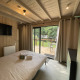 Camera accogliente in un lodge con pareti in legno, letto matrimoniale, TV e vista su terrazza e verde.
