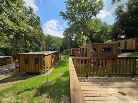 Houten chalets te midden van groen bij Cocoon de la Semois, Hameau de la Semois, België, omgeven door bomen.