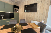 Modern lodge kitchen with wood panel walls, flat-screen TV, round dining table, and stylish chairs.