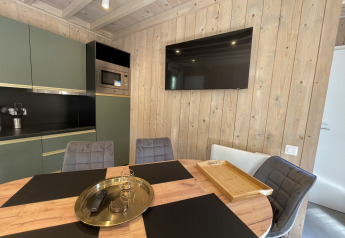 Modernes Lodge-Interieur mit Holzverkleidung, runder Esstisch, Flachbildfernseher und Küchenzeile.