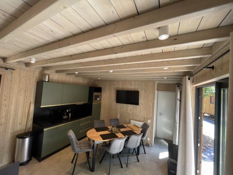 Modernes Küchen- und Esszimmer mit Holzwänden, Tisch und Stühlen in der Ecolodge im Hameau de la Semois, Belgien.