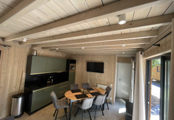 Modernes Küchen- und Esszimmer mit Holzwänden, Tisch und Stühlen in der Ecolodge im Hameau de la Semois, Belgien.