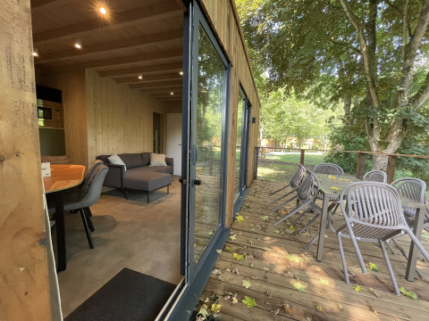 Interior and exterior of Ecolodge at Hameau de la Semois, Belgium, featuring terrace and outdoor seating area.