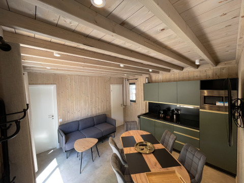 Interior view of a cozy ecolodge with modern kitchen, dining table and lounge in Hameau de la Semois, Belgium.