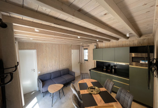 Interior view of a cozy ecolodge with modern kitchen, dining table and lounge in Hameau de la Semois, Belgium.
