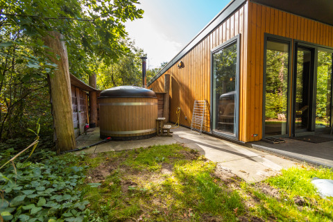 Area esterna della Wellness Lodge al Vakantiepark De Wiltzangh, Paesi Bassi, con vasca idromassaggio in legno.