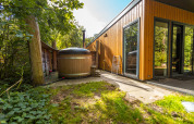 Espace extérieur de la Wellness Lodge à Vakantiepark De Wiltzangh, Pays-Bas, avec jacuzzi en bois et terrasse.