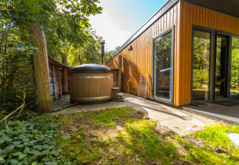 Udendørsområde ved Wellness Lodge i Vakantiepark De Wiltzangh, Nederlandene, med træbadekar og terrasse.