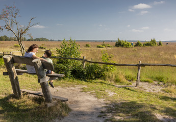 Mutter und Sohn sitzen auf einer Holzbank und genießen die Aussicht in einer Glamping-Unterkunft.