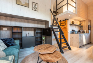 Interior of Tiny Borg at Vakantiepark De Wiltzangh, Netherlands, with loft, stairs, and a cozy kitchen area.