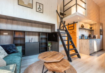 Interior of Tiny Borg at Vakantiepark De Wiltzangh, Netherlands, with loft, stairs, and a cozy kitchen area.