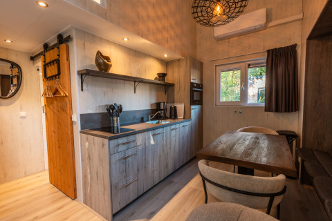 Gemütliches, modernes Tiny House mit Küche, Esstisch und Holzakzenten im Vakantiepark De Wiltzangh, Niederlande.